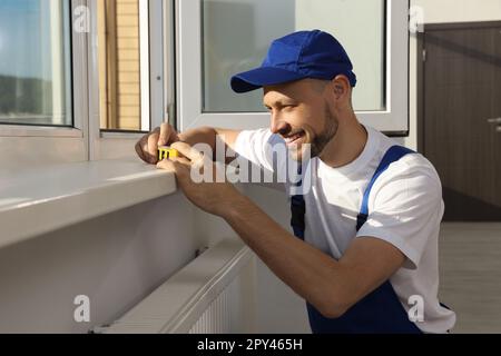 Worker using bubble level after plastic window installation indoors Stock Photo
