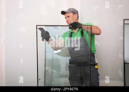 Worker in uniform preparing double glazing window for installation indoors Stock Photo