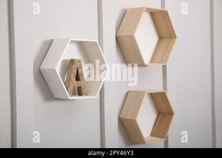 Honeycomb shaped shelves with decorative wooden letter on white wall Stock Photo
