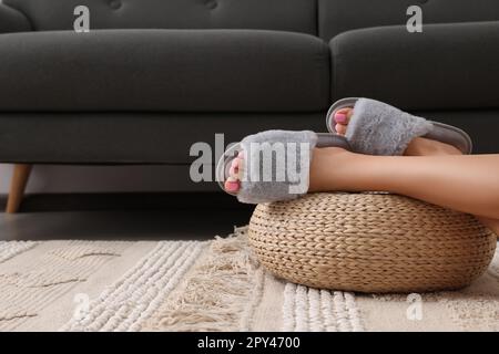 Woman wearing grey soft slippers in room, closeup. Space for text Stock Photo