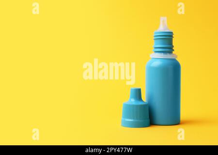 Bottle of medical drops on yellow background. Space for text Stock Photo