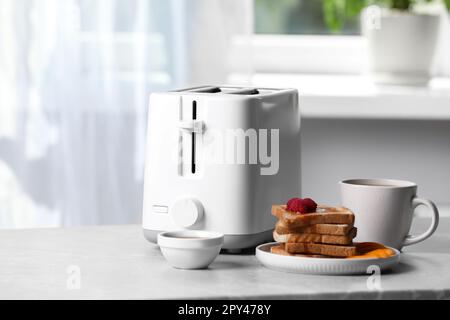 Toaster, roasted bread and coffee on light gray marble table, space for text. Tasty breakfast Stock Photo