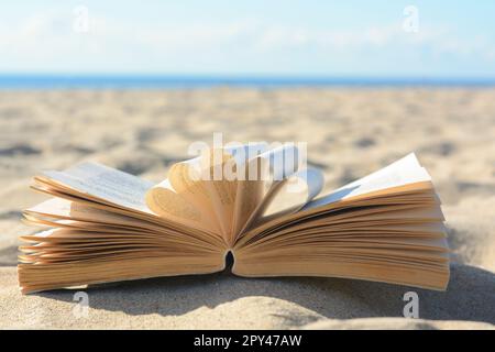 Open book on sandy beach near sea Stock Photo