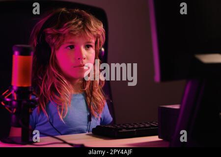 Child plays a video game on the pc computer screen. School, study, online learning concept. Gamer play computer games. Neon lighting. Stock Photo