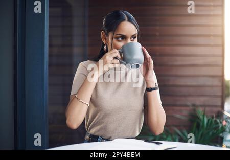 Enjoying a little caffeine break. an attractive young businesswoman drinking her coffee while working in the office. Stock Photo