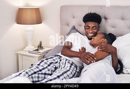 Should we stay in today. an affectionate couple relaxing on their bed wearing pajamas. Stock Photo