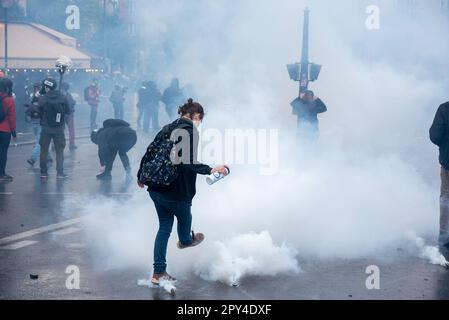 Paris, France. 01st May, 2023. A protester kicks away tear gas capsules during the Labor Day demonstration in Paris. Hundreds of thousands of people attended on the Labor Day protest in Paris to demand to stop the very unpopular pension reform. The protest escalated violent in a very short while. The protesters and the police clashed many times during the day. The protesters broke into the shops and light up anything flammable. The police deployed water cannon and tear gas to stop the riot. Credit: SOPA Images Limited/Alamy Live News Stock Photo