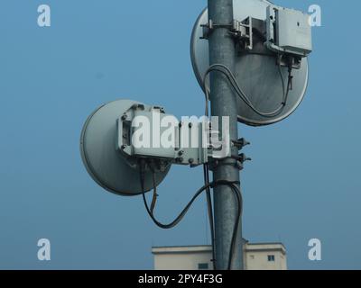 Microwave radio Link antenna mounted on a radio tower with blue sky in the background side view portrait Stock Photo