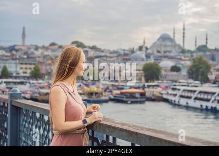 Young tourist woman on Galata bridge, Golden Horn bay, Istanbul. Panorama cityscape of famous tourist destination Bosphorus strait channel. Travel Stock Photo