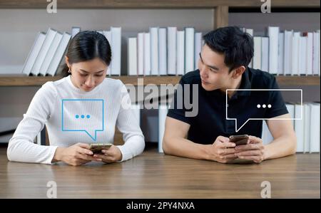 Young asian lovers using smartphone typing live chat chatting. Social network concepts, chatting conversation in chat box icons pop up. Social media m Stock Photo