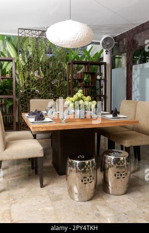 Massive wooden dining table with beautiful flower centerpiece on the balcony Stock Photo