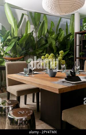 Massive wooden dining table with beautiful flower centerpiece on the balcony Stock Photo