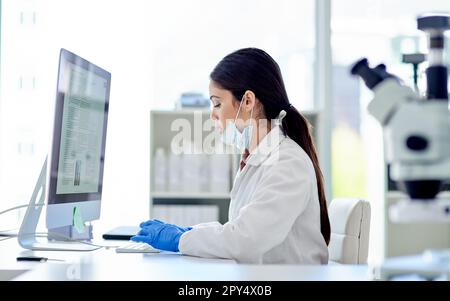 Doing some more research online. a young scientist working on a computer in a lab. Stock Photo