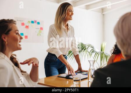 Young businesswoman having a meeting with her team. Happy team leader brainstorming with her colleagues in a boardroom. Group of creative businesswome Stock Photo