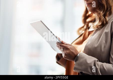 Set your own trends in the business world. an unrecognizable businesswoman using a digital tablet in her office. Stock Photo