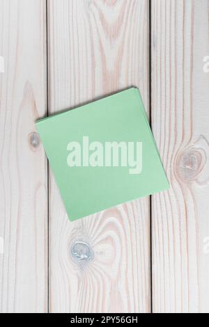 Flat lay of empty blank green sticker sticky note on grey wooden table. Note, paper, reminder, information, memory. Stock Photo