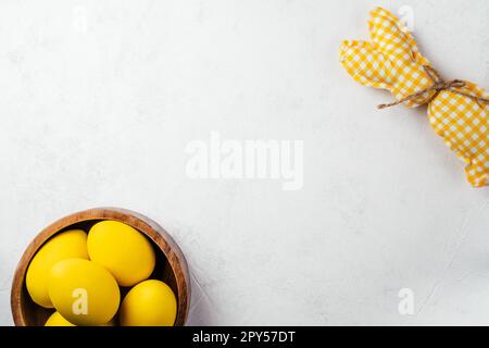 Easter white postcard for celebration holiday,one handmade square bunny and yellow chicken colored eggs in wooden plate. Stock Photo