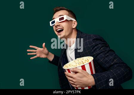 guy in 3d glasses eating popcorn on pink background Stock Photo