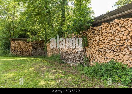 Wood pile, stacked and cut firewood, stored in an open shed Stock Photo