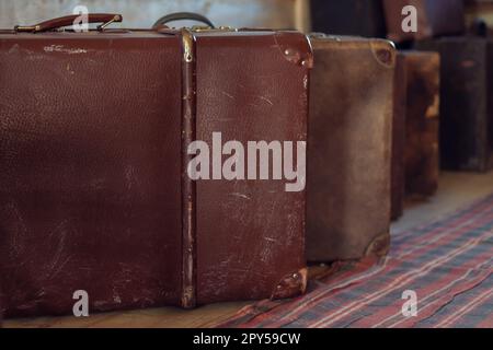 Row of antique shabby suitcases on floor of wooden countryside house. Brown leather old fashioned baggage for travelling Stock Photo