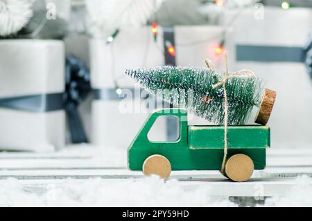 wooden toy car carrying a christmas tree on shiny lights background Stock Photo