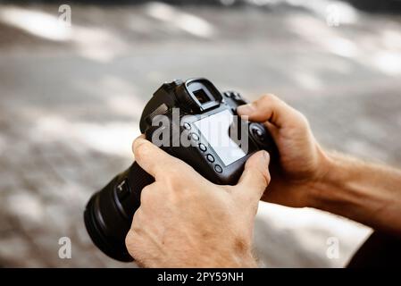 Male hands holding photo camera, professional camera in hand Stock Photo