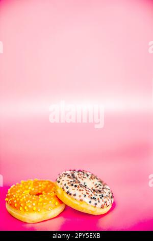Sweet donuts stacked in a stack on a pink background. Copy space, various glaze and sprinkels chocolate chip, snack fast food sweets concept Stock Photo