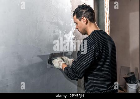 man applies insulation to a bathroom wall Stock Photo