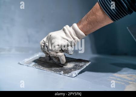 spreading the insulation on the concrete on floor with a trowel Stock Photo