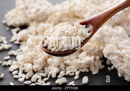 Closeup of rice koji and wooden spoon placed on black background. Koji. Stock Photo