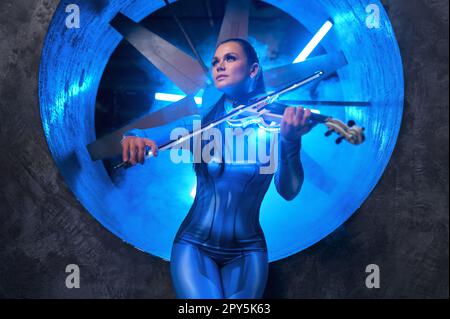 Young woman playing electronic violin in neon glowing light Stock Photo