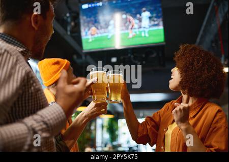 Happy friends drinking beer and cheering together in sports bar Stock Photo
