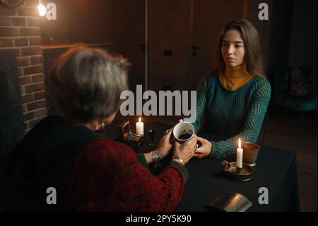 Young woman visiting gypsy witch for divination on coffee grounds Stock Photo