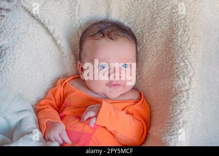 Newborn european white baby in orange clothes Stock Photo
