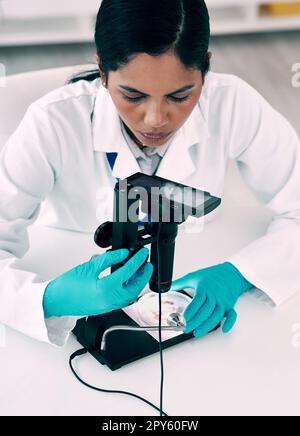 Digital microscopes make analysing samples much simpler. High angle shot of an attractive young female scientist using a digital microscope while Stock Photo