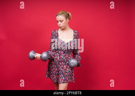 Strong sportswoman in boxing gloves prepared high kick. Isolated on white, red, yellow background Stock Photo