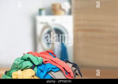 Stack or pile of colorful dirty clothes on table ready for the laundry in front of abstract blurred bath background with copy space. For your product display montage. Stock Photo