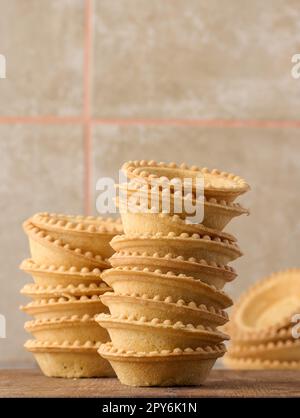 Stack of empty baked round canape baskets on a wooden board, round empty tartlets Stock Photo