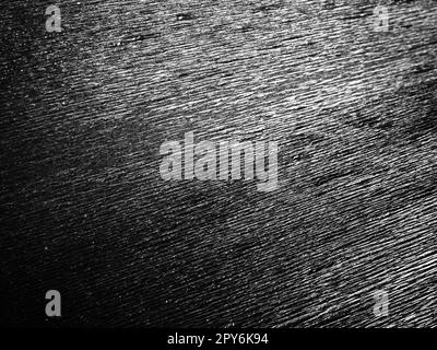 Black or gray corrugated paper. Uneven surface. Abstract monochrome background. Wavy edges of the paper sheet. Lighting gradient. Corrugated texture Stock Photo