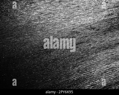 Black or gray corrugated paper. Uneven surface. Abstract monochrome background. Wavy edges of the paper sheet. Lighting gradient. Corrugated texture Stock Photo