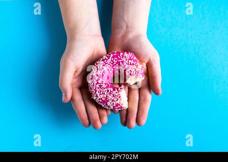 Hand holding a half eaten sweet pink donut isolated. Half eaten donut isolated. Stock Photo