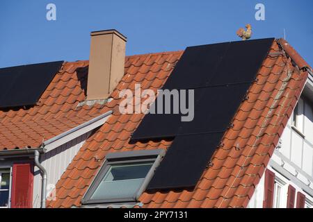 Half-timbered house with solar panels on the tiled roof. clear sky Stock Photo