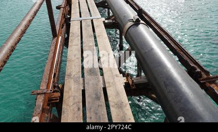 View of old deck,  by the Mediterranean Sea, Israel .Remains of a rusted handrails on a waterfront. Metal corrosion due to frequent exposure to sea water close-up Stock Photo