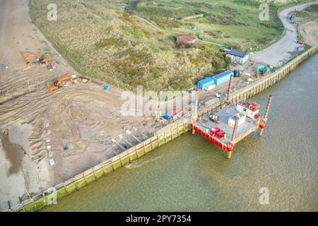 Mobile rig positioned for repair works to the damaged sea wall at the entrance to the River Arun on west bank in Littlehampton. Aerial photo. Stock Photo