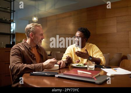 Two colleagues discussing plans while having meeting during business lunch in restaurant Stock Photo
