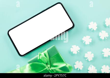 overhead flat lay of paper cut clover leaves festive decor and mobile phone blank screen Stock Photo