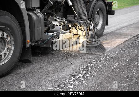 Close up view of heavy duty street cleaning vacuum machine known as street sweeper brushing the streets clean. Stock Photo