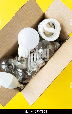 A set of different types of LED and incandescent lamps in a craft box on a yellow background. Stock Photo