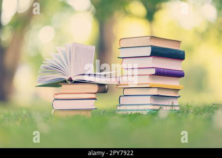 Stack of the books standing on the green meadow outdoors. Stock Photo