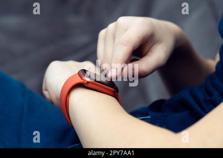 Closeup cropped man hand with red Wireless smart watch, electronic gadgets, wrist watch technology. Pulse check, fitness Stock Photo
